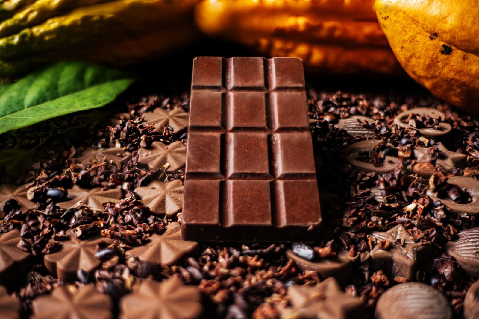 Barra de chocolate Q’ínti rodeada de cacao y nibs